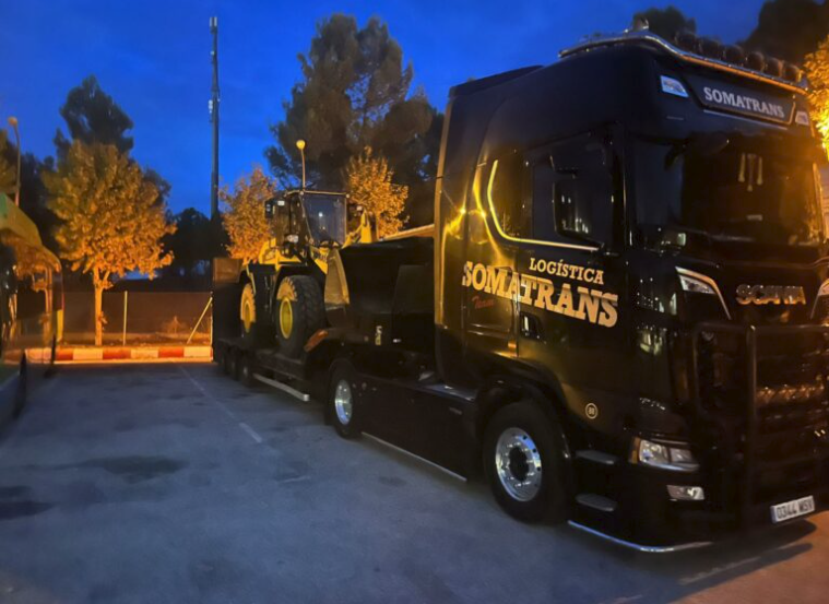 Camión negro de Logística Somatrans transportando maquinaria por la noche