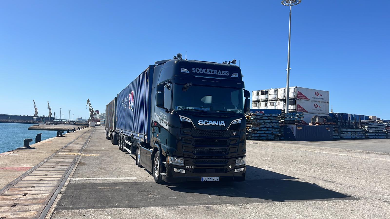 Camión negro de Somatrans con semirremolque en zona portuaria